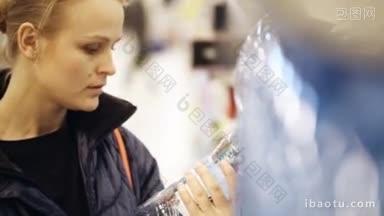一位年轻的女士在超市购物，她选择了一瓶<strong>矿泉水</strong>，并把它放在她的购物篮里